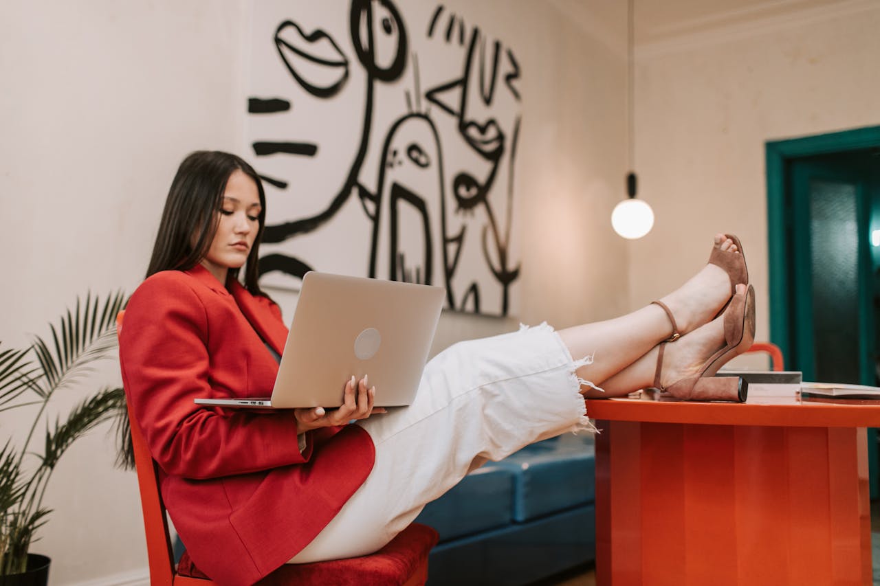 About Confident businesswoman in heels working on a laptop at a stylish office desk.